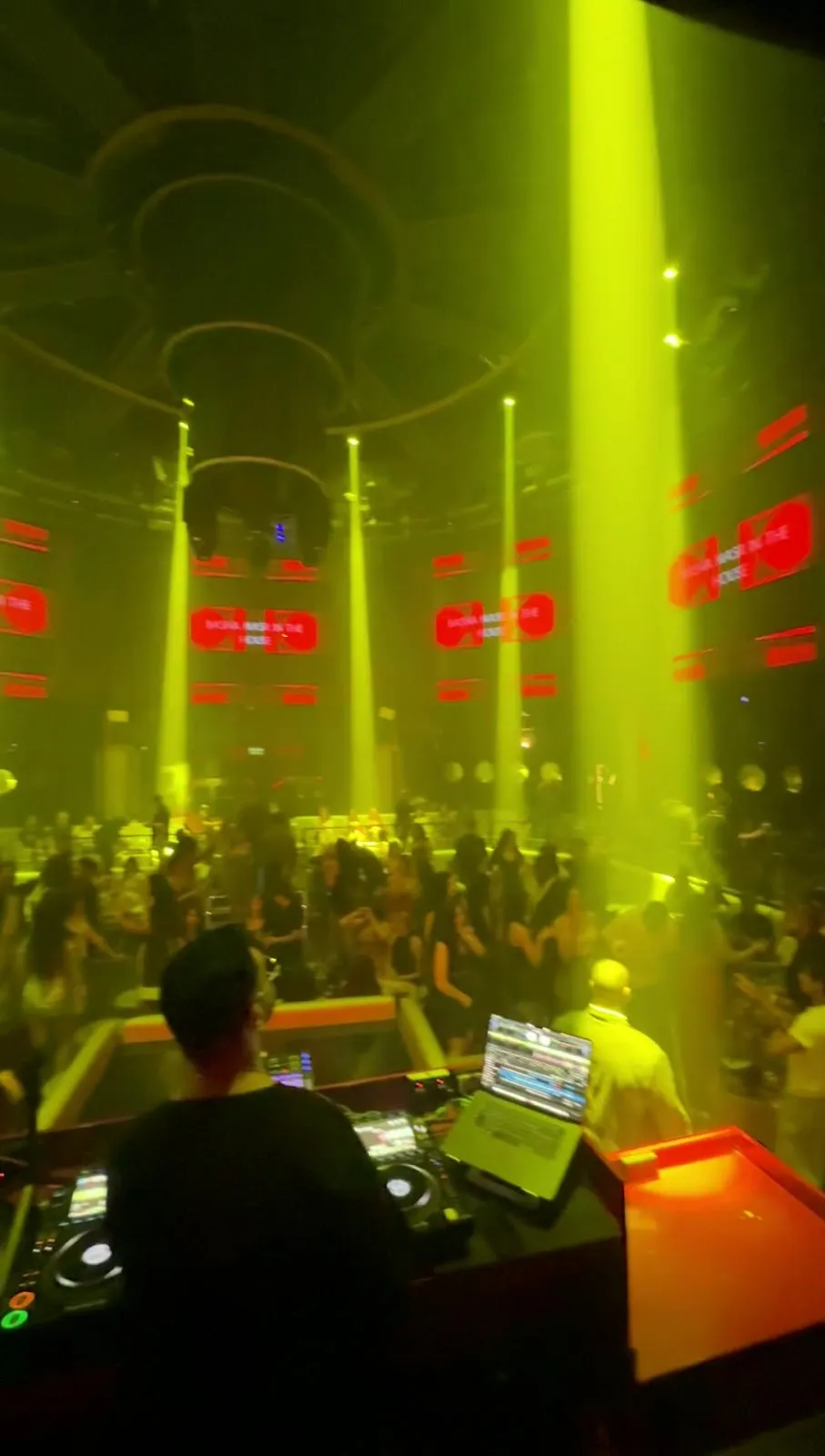 DJ console bathed in green stage lighting during a set